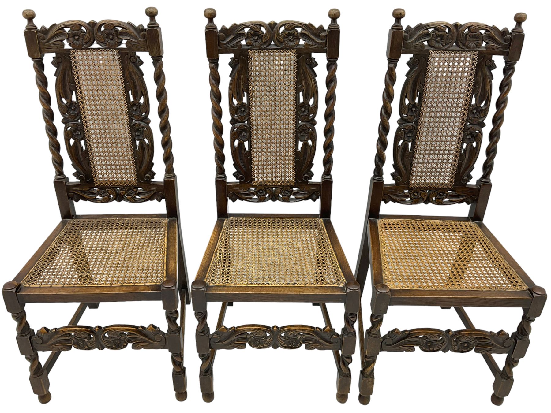 Set of seven (5+2) 19th century Carolean design oak dining chairs, scroll leaf and flower head carved cresting rail over spiral turned uprights and cane work back, the cane work seat on spiral turned supports united by plain stretchers, scrolled leaf carved middle rail 