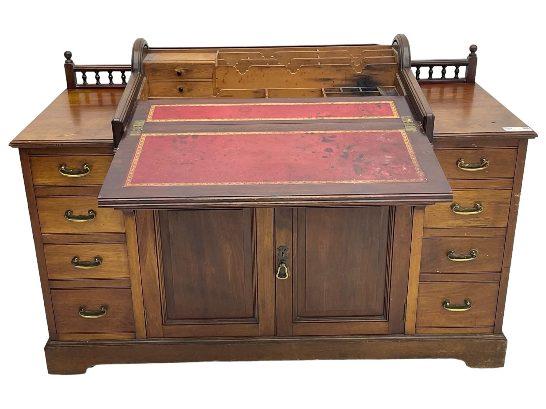 Victorian walnut clerk's desk, raised central section with tambour roll over hinged top, the interior fitted with leather inset writing surfaces, small drawers, document divisions and pen and ink stand, central drawer over double panelled cupboard, flanked by two banks of four graduating drawers, on bracket feet 