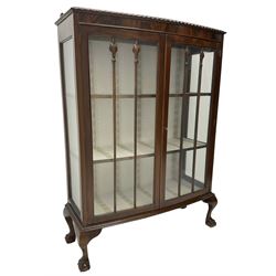 Early 20th century figured walnut bow-front display cabinet, enclosed by two glazed doors, on ball and claw cabriole feet