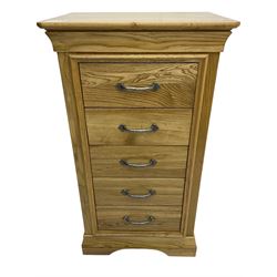 Contemporary light oak pedestal chest, moulded cornice and chamfered rectangular top with rounded fronts, over five drawers with metal handles and cock-beaded surrounds, on bracketed plinth base