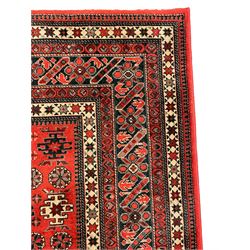 Persian design red ground rug, the field decorated with geometric motifs, repeating multiple band border 