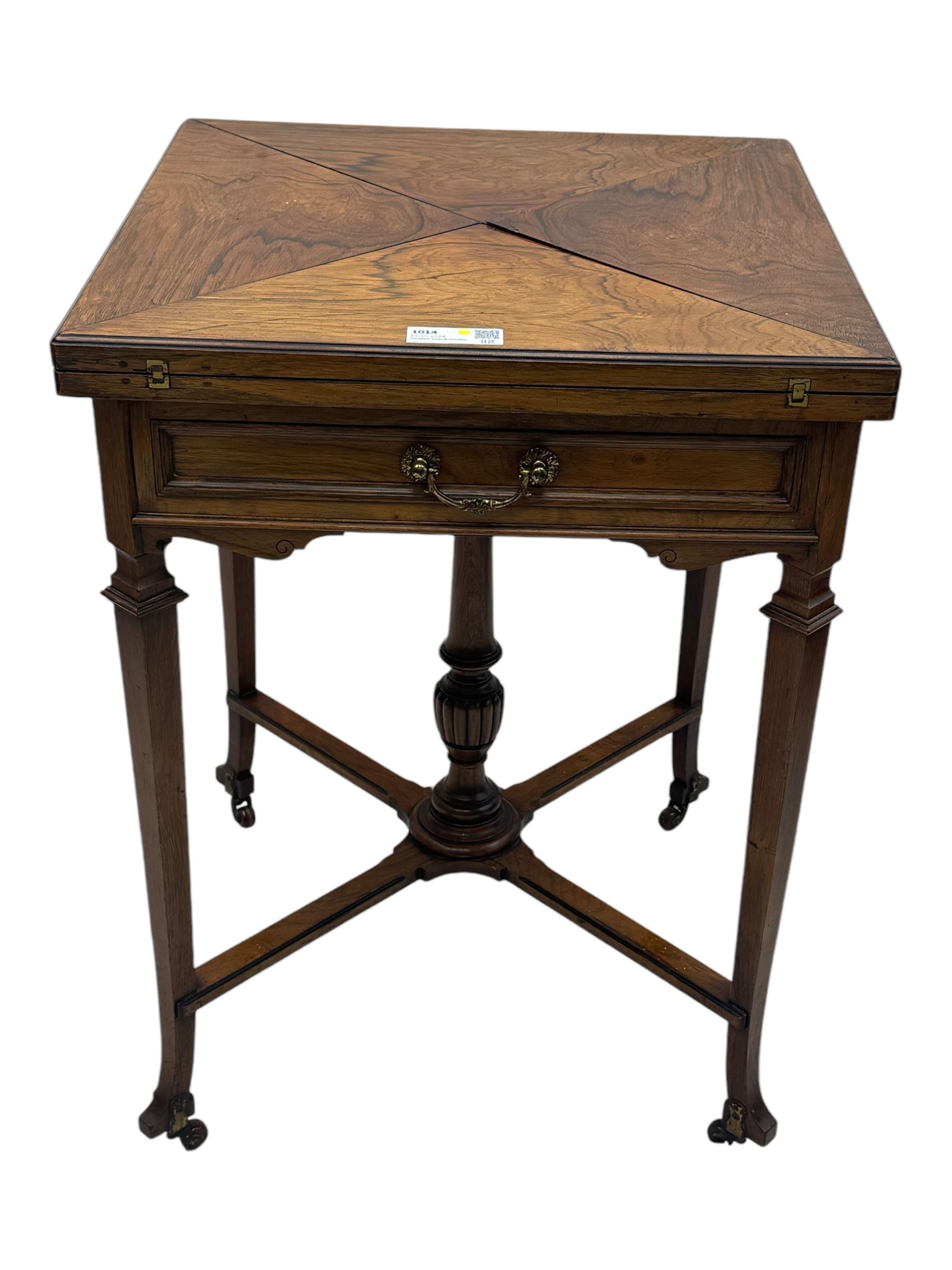 Victorian rosewood envelope games table, the moulded square top with four triangular hinged leaves, revealing inset baize playing surface and sunken counter wells, fitted with single frieze drawer, on square tapering supports united by x-framed stretchers and turned central column, on brass and ceramic castors 