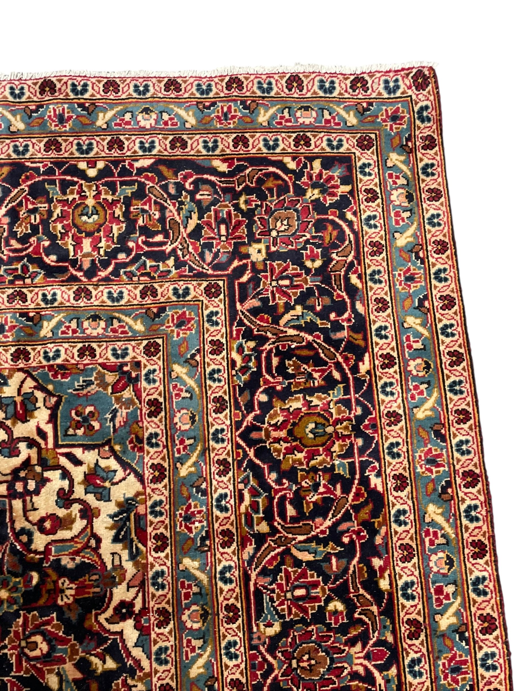 Persian Kashan crimson ground carpet, floral pattern pole medallion surrounded by trailing branches with foliate motifs and palmettes, scrolling border decorated with stylised plant motifs, within multiple guard stripes