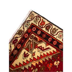 Persian crimson ground rug, the field decorated with three medallions within stepped borders, decorated all over with small stylised plant motifs, trailing flower head outer band and floral pattern border 