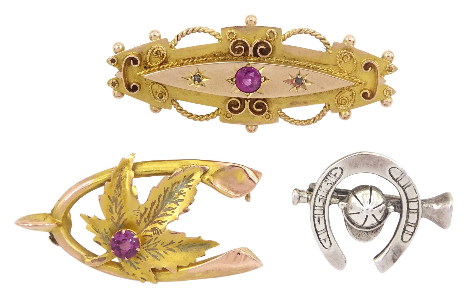 Two early 20th century 9ct gold garnet brooches and a silver jockey hat and horseshoe brooch