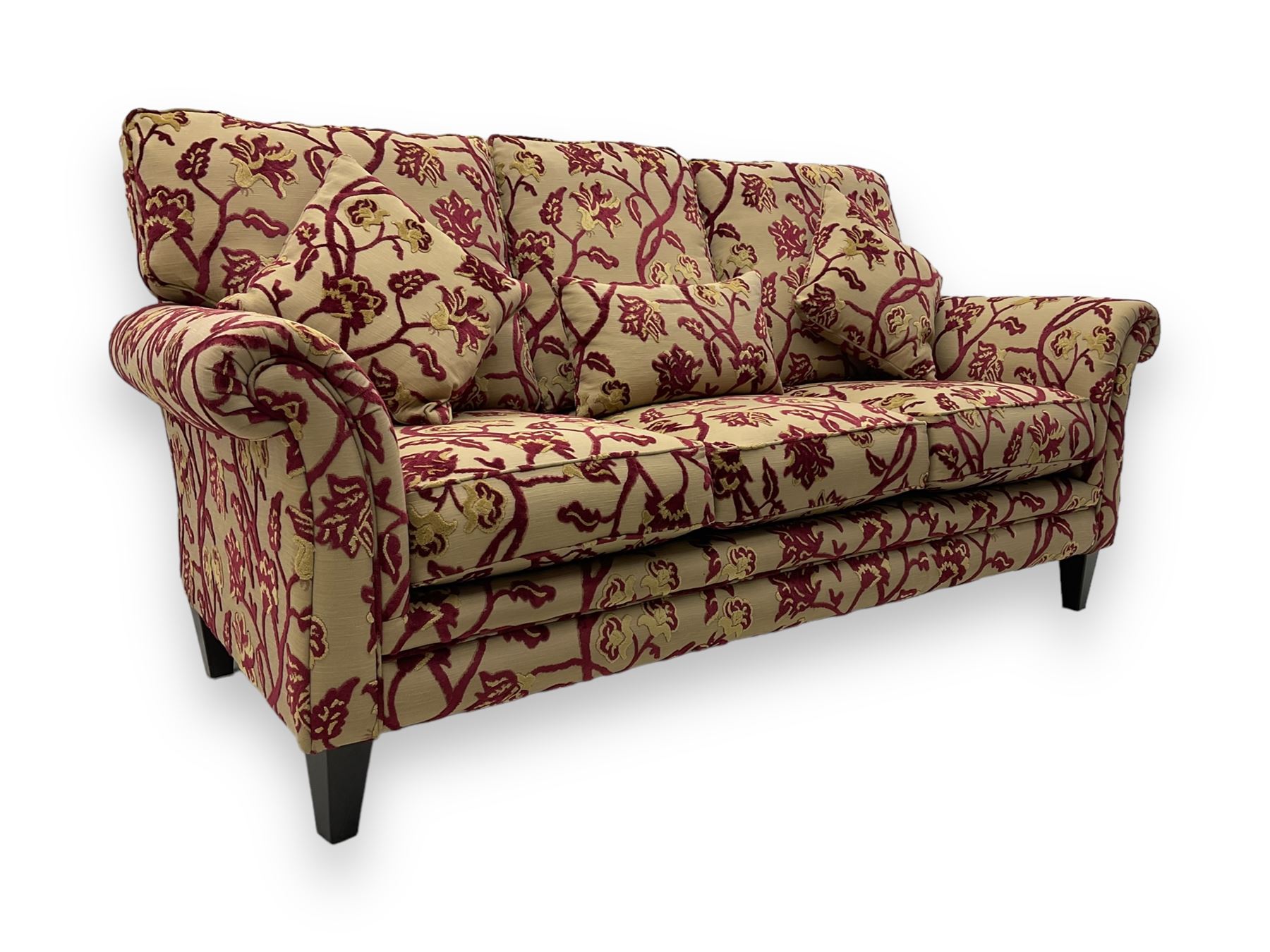 Contemporary upholstered three-seat sofa, scroll arms and loose cushions, embossed beige ground fabric with red and gold floral motifs, on tapered wooden supports