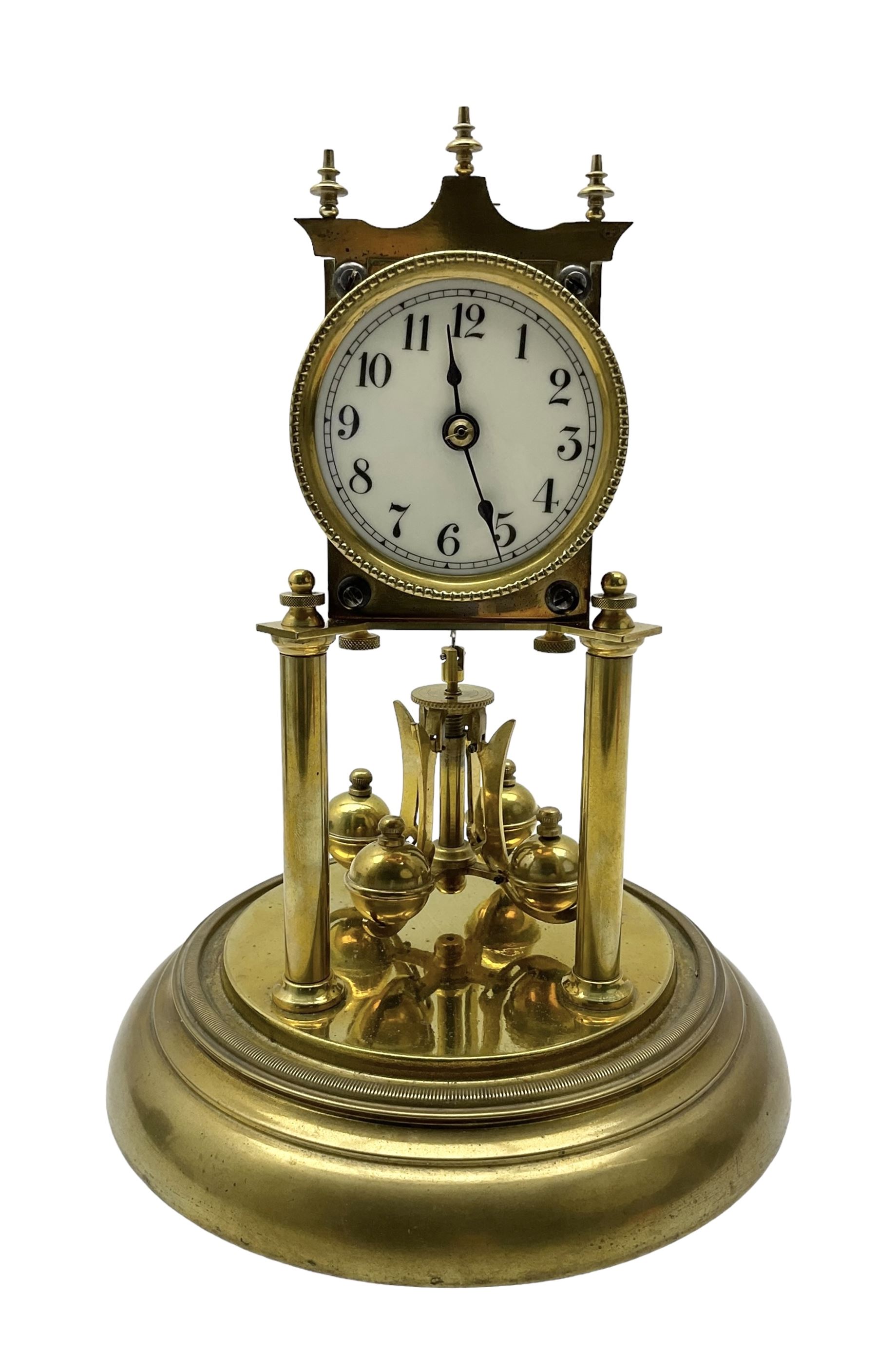 Continental- early-20th century torsion clock under a glass dome, movement raised on two pillars on a circular brass base, with an enamel dial, Roman numerals and spade hands, oscillating four ball circular pendulum. Torsion spring intact.