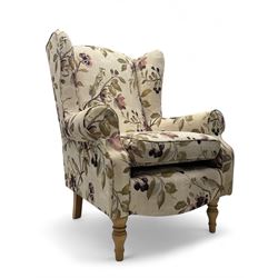 Hardwood-framed wingback armchair, upholstered in cream floral pattern fabric, on turned front feet