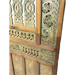 Early 20th century Javanese teak and hardwood door panel or room divider, rectangular panelled form with moulded frame and pegged construction, carved and pierced with scrolling decoration and flower head motifs, shaped and pierced splats with interlocking pattern