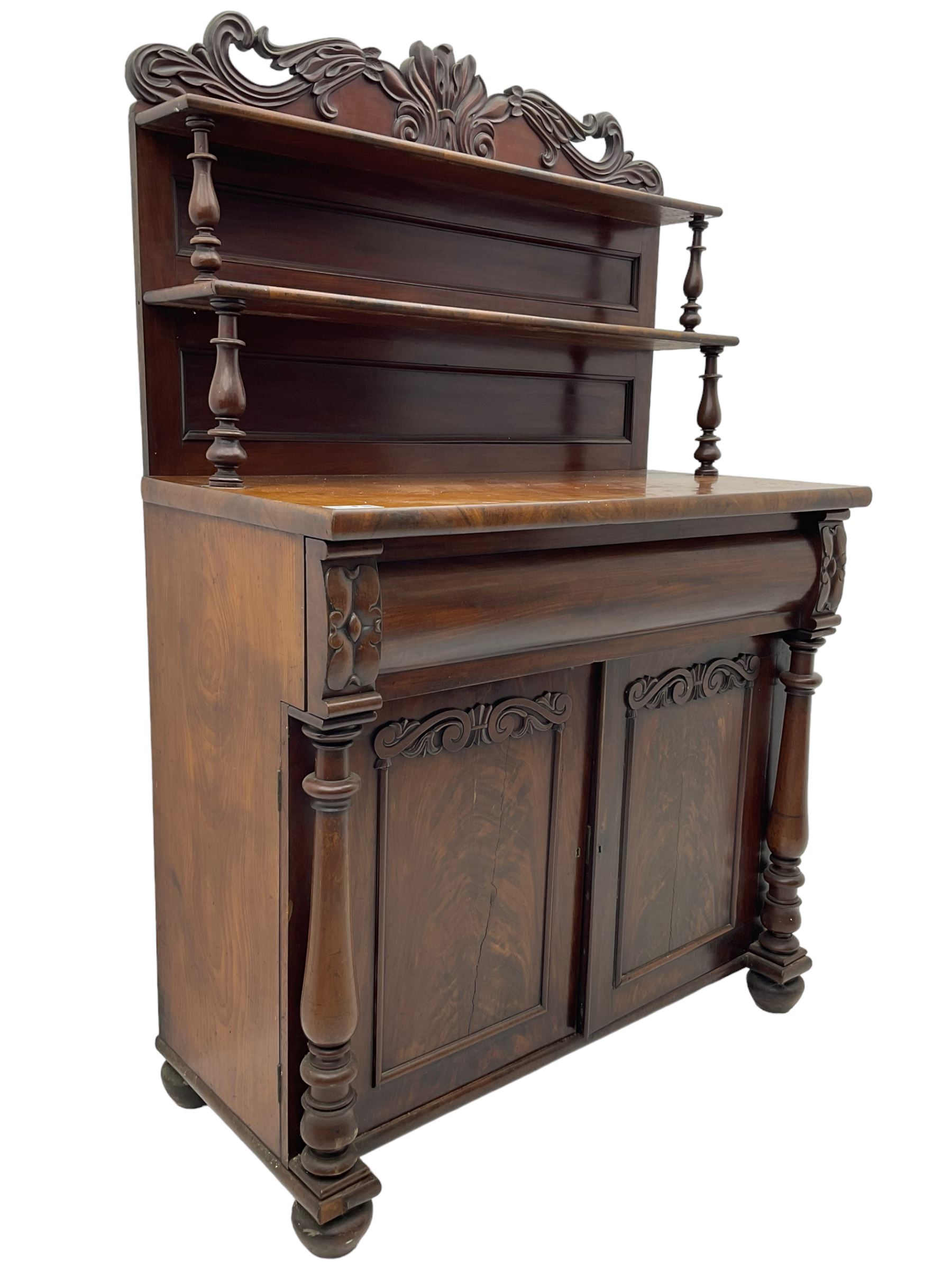 Victorian mahogany chiffonier, raised shaped pediment carved with scrolled extending foliage, two graduating shelves on turned supports, rectangular top over drawer and double cupboard, turned column pilasters, on turned feet 