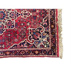 Persian Hamadan crimson ground rug, central floral pole medallion with matching spandrels, the guarded indigo border with interlaced palmettes