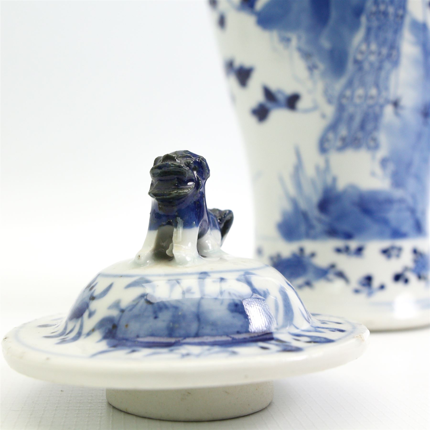 Pair of 19th/ early 20th century Chinese blue and white vases and covers, each of baluster form, painted in underglaze blue with peacocks stood on a rocky base amid blossoming peony and prunus flowers, the covers with dogs of fo finials, four character Kangxi marks beneath, H33cm 