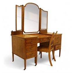 Waring & Gillow Ltd. - Edwardian satinwood dressing table, raised bevelled triple mirror back on square supports, over frieze inlaid with geometric stringing in ebony, moulded drop-centre table with stringing, fitted with seven drawers, reeded and foliate cast handles and square leaf cast handle plates, on square tapering supports terminating to brass castors, the centre drawer with metal maker's plaque and maker's stamp for 'Waring & Gillow, Ltd.', the top three drawers fitted with Chubb locks, the remaining drawers fitted with locks stamped 'Gillows Lancaster', together with associated chair 