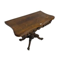Victorian rosewood serpentine tea table, shaped fold-over and swivel top, the frieze decorated with carved scrolling foliate mounts, on octagonal faceted baluster pedestal, four scroll carved splay supports