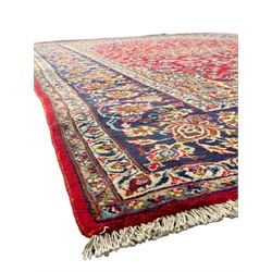 Persian Kashan red ground rug, the field decorated with a central floral medallion surrounded buy scrolling vine motifs and palmettes, the main border featuring a series of stylised floral motifs against a dark blue ground, enclosed by multiple guard stripes with alternating floral and geometric designs