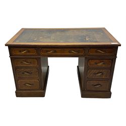 20th century oak twin pedestal desk, rectangular top with inset leather writing surface, fitted with nine drawers with chamfered edges to the raised panels, each with curved brass handles with scroll ends and keyholes, fluted detailing to the top and between the drawers, on moulded plinth base with castors