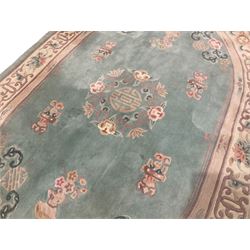 Chinese pale turquoise ground washed woolen rug, oval form decorated with bouquets of floral designs and Chinese characters, enclosed by a wide guard band