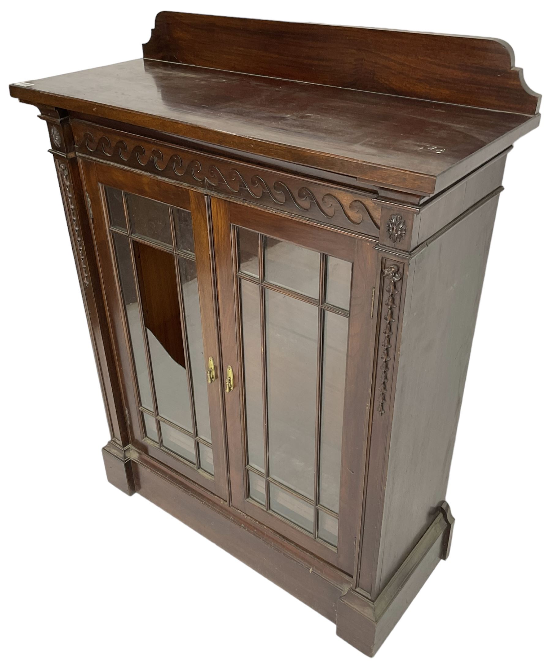 19th century mahogany display cabinet, rectangular top over frieze decorated with Vitruvian scroll mount, enclosed by two astragal glazed doors, the upright rails decorated with trailing bellflowers, on moulded plinth