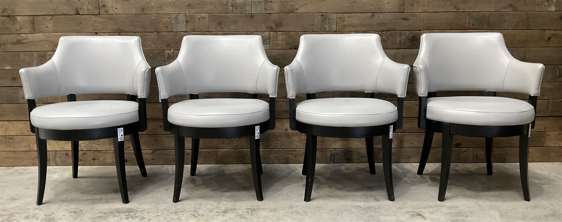 Four ebonised framed tub shaped armchairs, upholstered in grey fabric