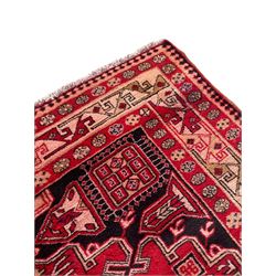 Persian Hamadan indigo and crimson ground rug, the field filled with three shaped medallions, overall geometric design, decorated with sandikli and hac motifs, geometric main border with repeating hooked motifs, within guard stripes decorated with small flower heads, outer crenelated fence band 