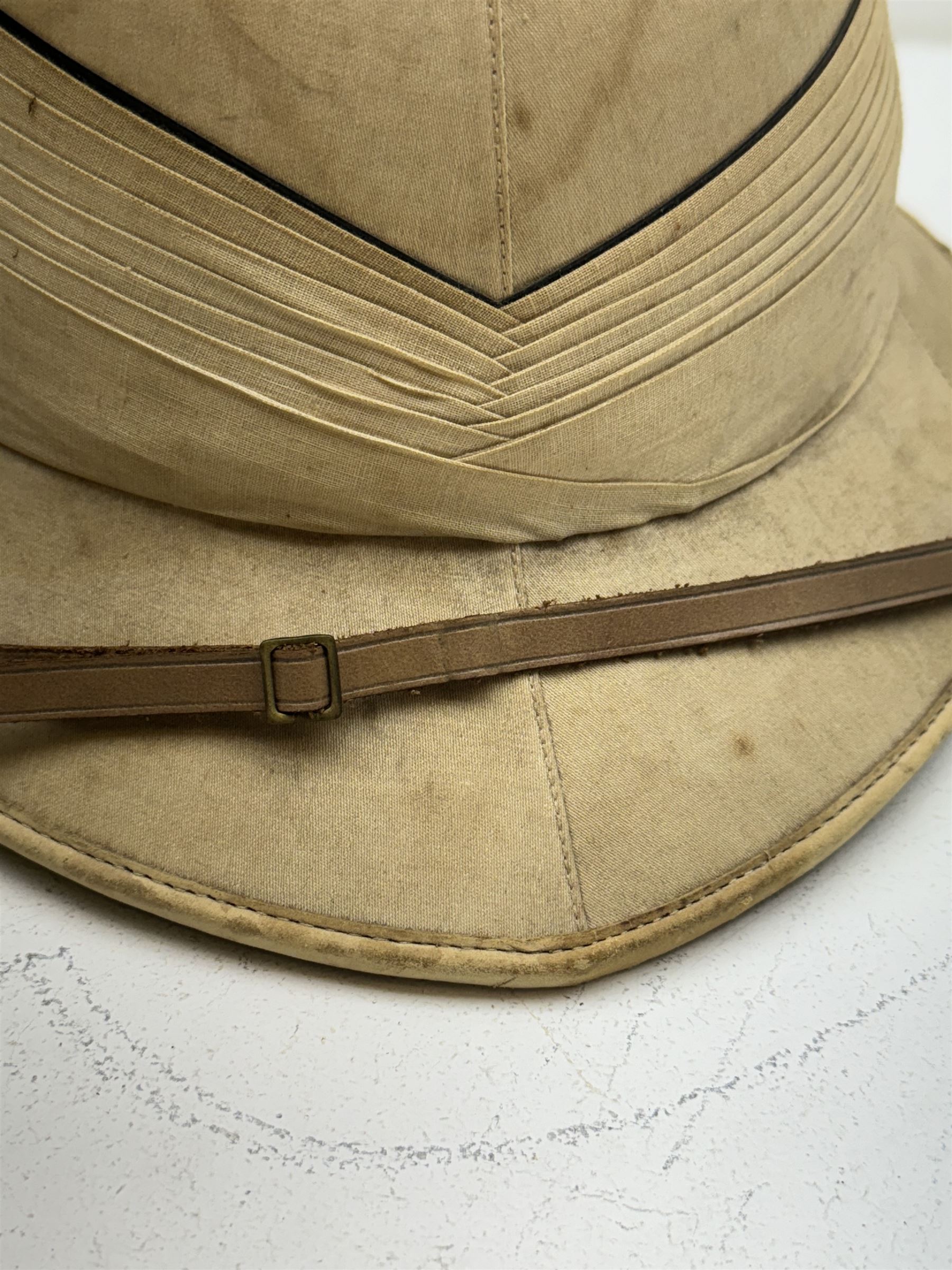 WWII Royal Navy officers sun helmet with large folded pagri and black top line, interior with green cloth covering to the peaks and original leather sweatband, with makers label 'Gieves Ltd London', with its original storage tin with indistinct painted lettering to the front 