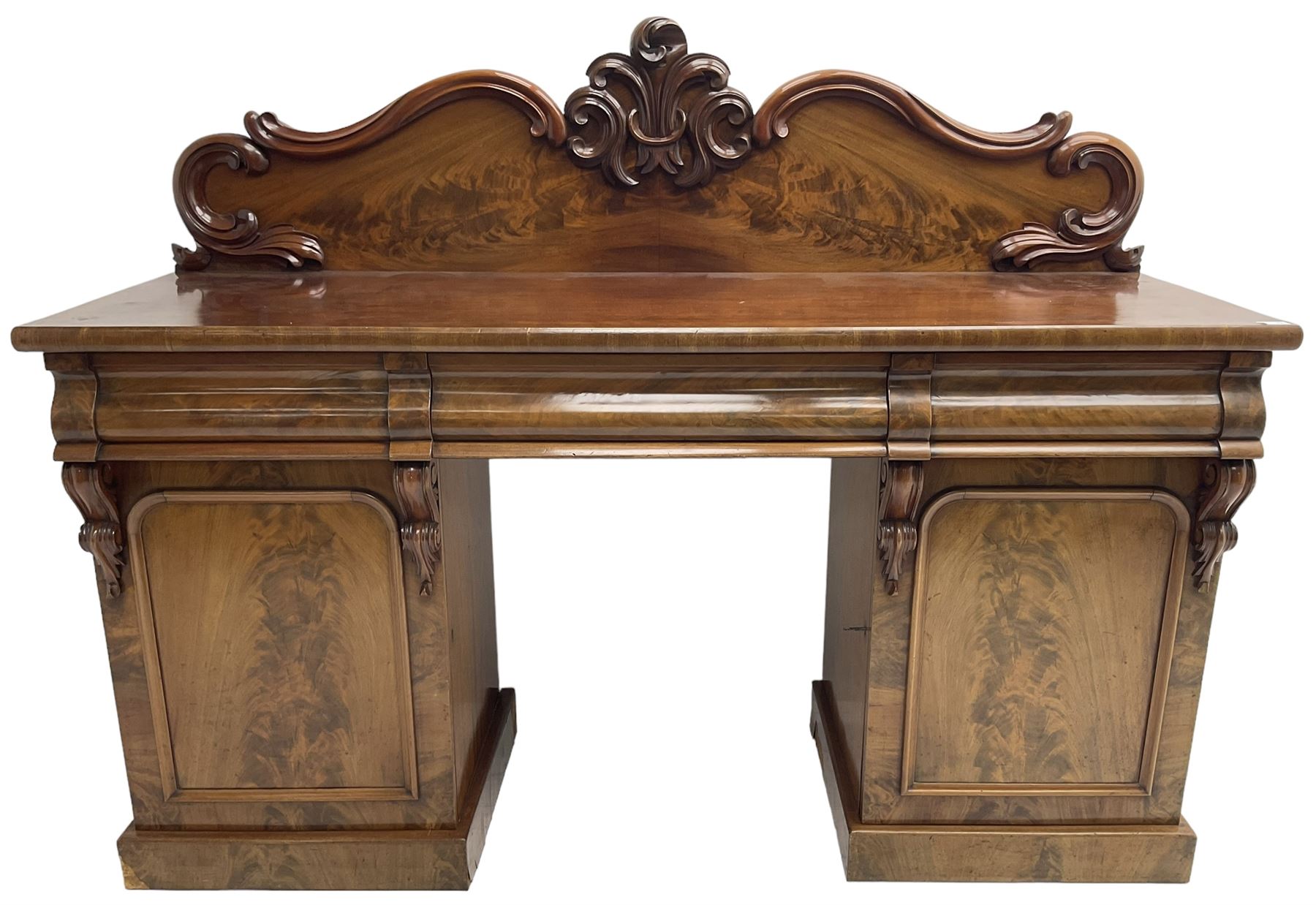 Victorian mahogany twin pedestal chiffonier, raised back with decorated with scrolling foliate motifs, fitted with three cushion drawers, the arched panelled pedestals enclosing shelves and sliding trays