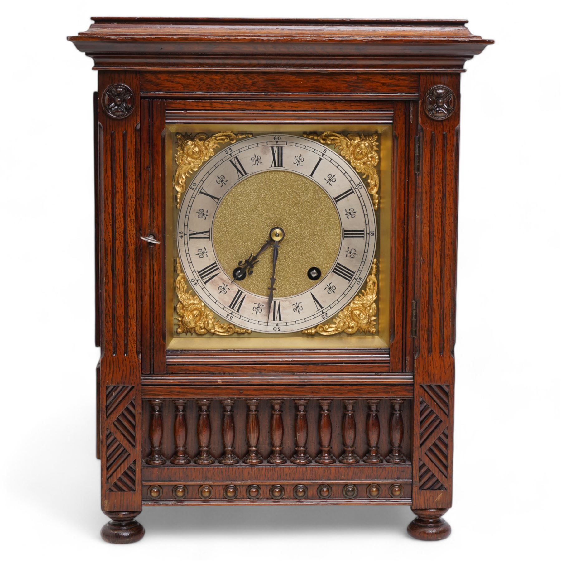 Lenzkirch - late 19th century German oak cased 8-day quarter striking mantle clock, with a flat top and moulded cornice beneath, carved decoration with a turned baluster gallery to the front, raised on bun feet, square brass dial with a matted centre and cast cherub spandrels, silvered chapter with Roman numerals and fleur-di-Lis steel hands, two train going barrel movement striking the quarters and hours on two coiled gongs. With pendulum and key.