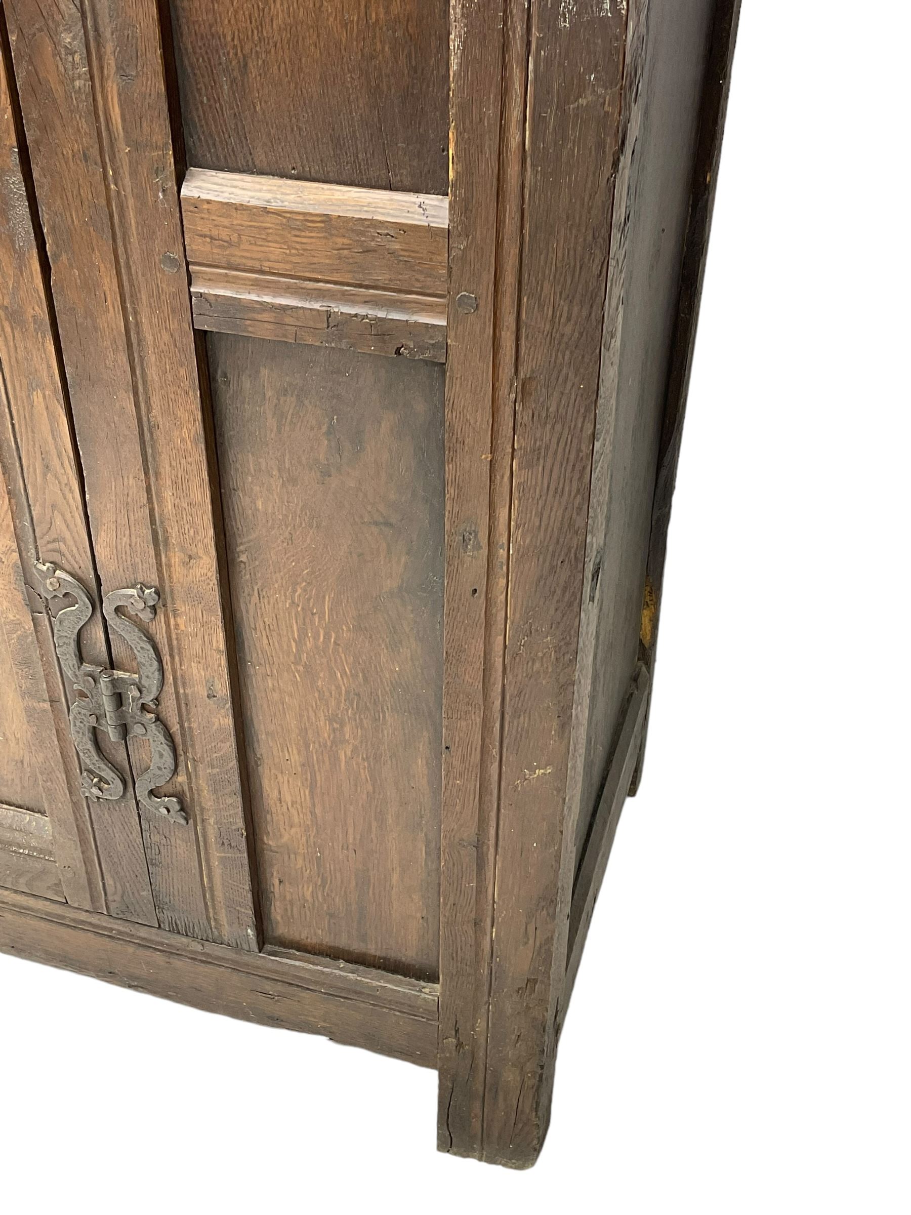 17th century and later oak hall cupboard, panelled front and sides with moulded frame, enclosed by single door with wrought metal hinges and handle, the interior fitted with hooks, on stile supports 