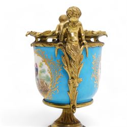 19th century French Sevres style porcelain and gilt brass urn, the body painted with panels of exotic birds and floral sprays within gilt borders on a bleu celeste ground, the handles formed as two cherubs seated upon grasses, upon a laurel leaf cast pedestal base, H20.5cm 