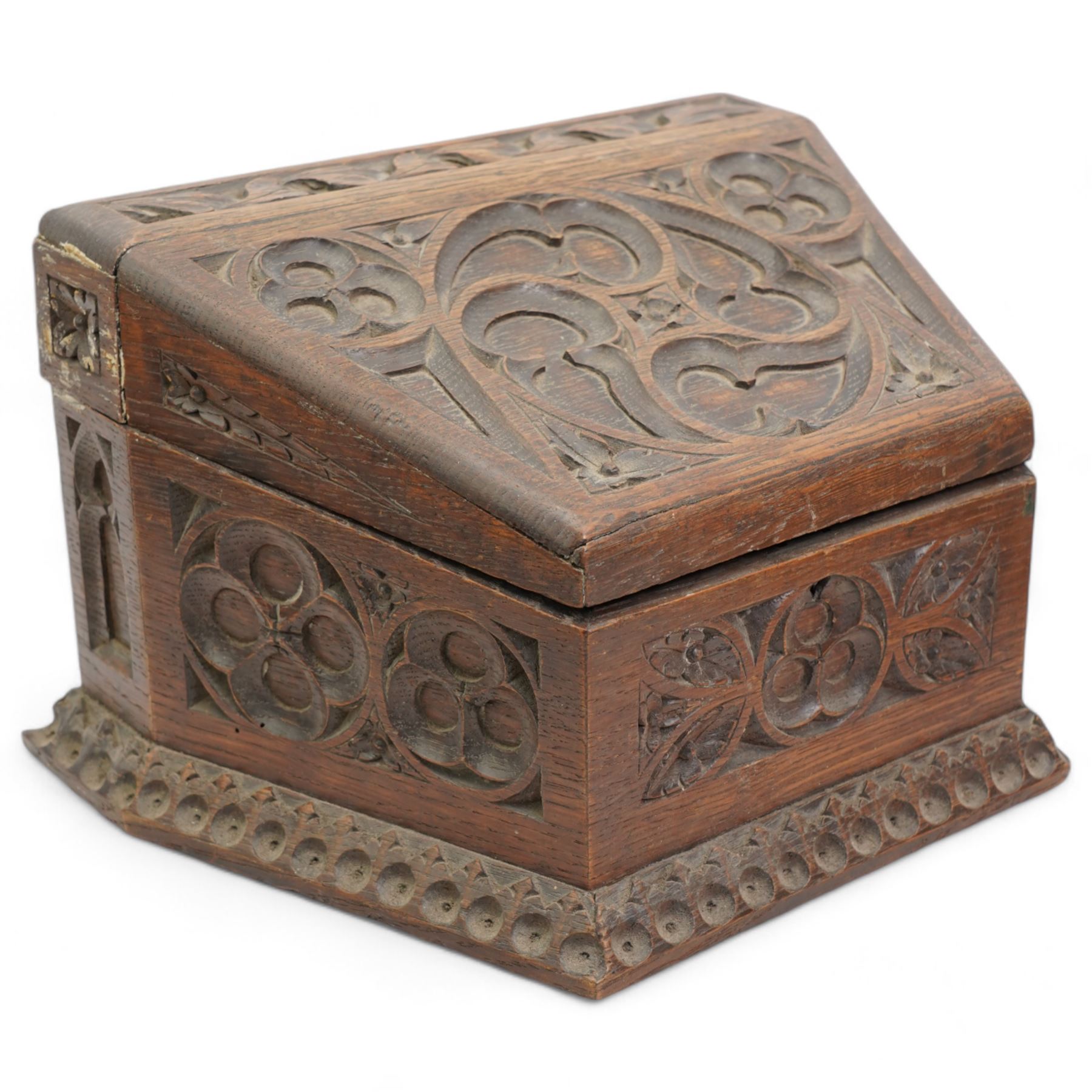 Late Victorian oak stationery box carved with Gothic and foliate panels, hinged sloping lid and divided interior with the trade label of H Ladd, 34 Trinity St. Cambridge, Stationer & Die Sinker W26cm