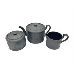 Late 19th/early 20th century Wedgwood black basalt three piece tea set, comprising teapot, sucirer and cover, and milk jug, each of cylindrical form, decorated with a vignette of classical maidens, each impressed beneath Wedgwood, Made in England, teapot H10cm