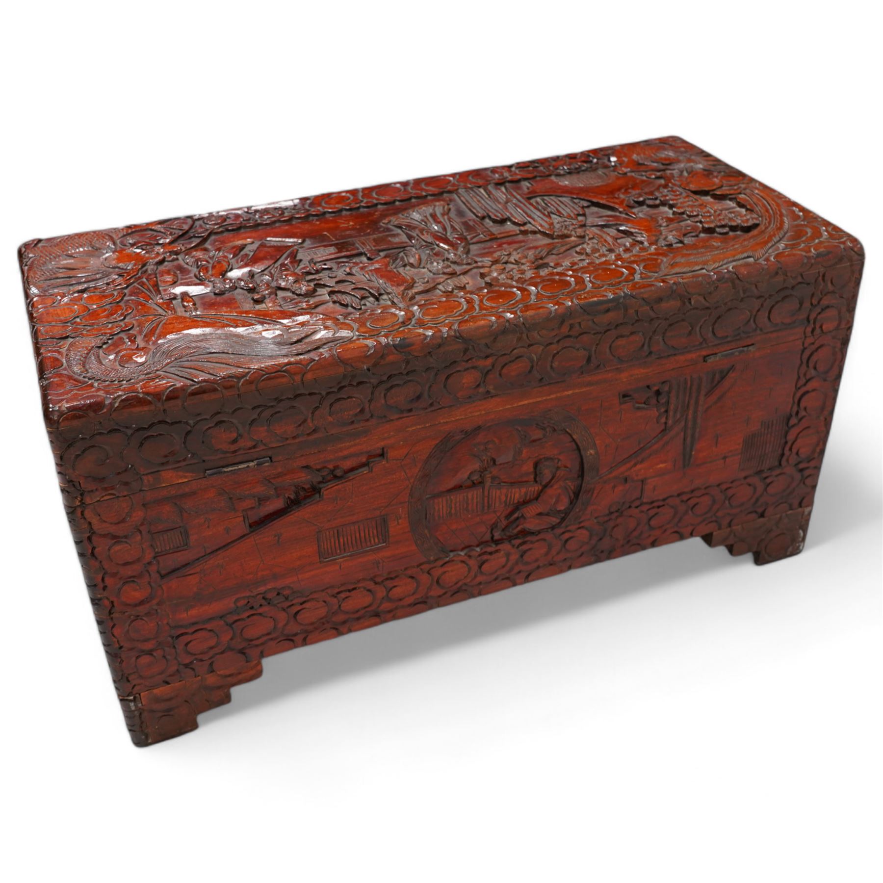 Chinese heavily carved and lacquered camphor wood blanket chest, rectangular hinged top, carved all-over with traditional figural and pagoda scenes with exotic birds, enclosed by a border of stylised clouds