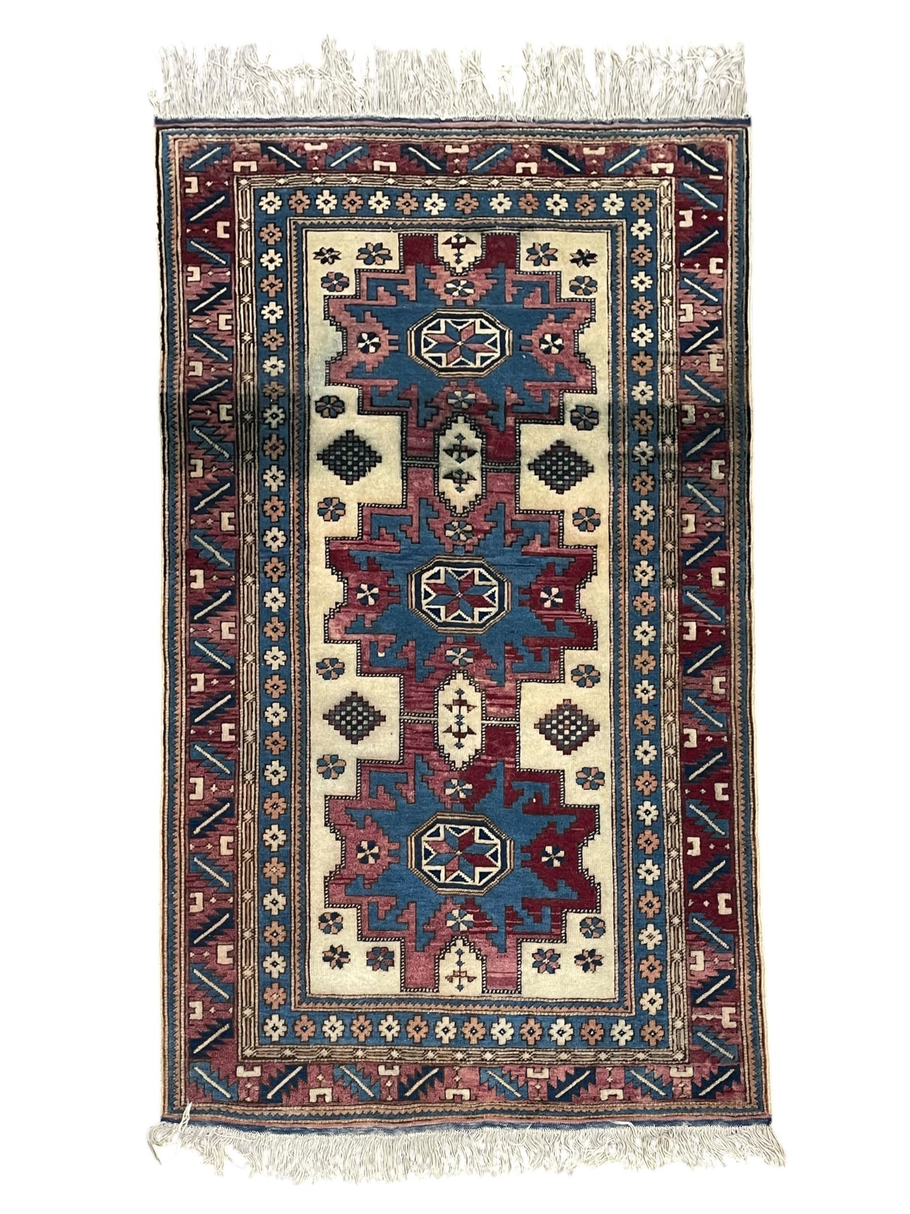 Turkish camel ground rug, three medallions surrounded by geometric motifs, the border decorated with stylised leaf motifs