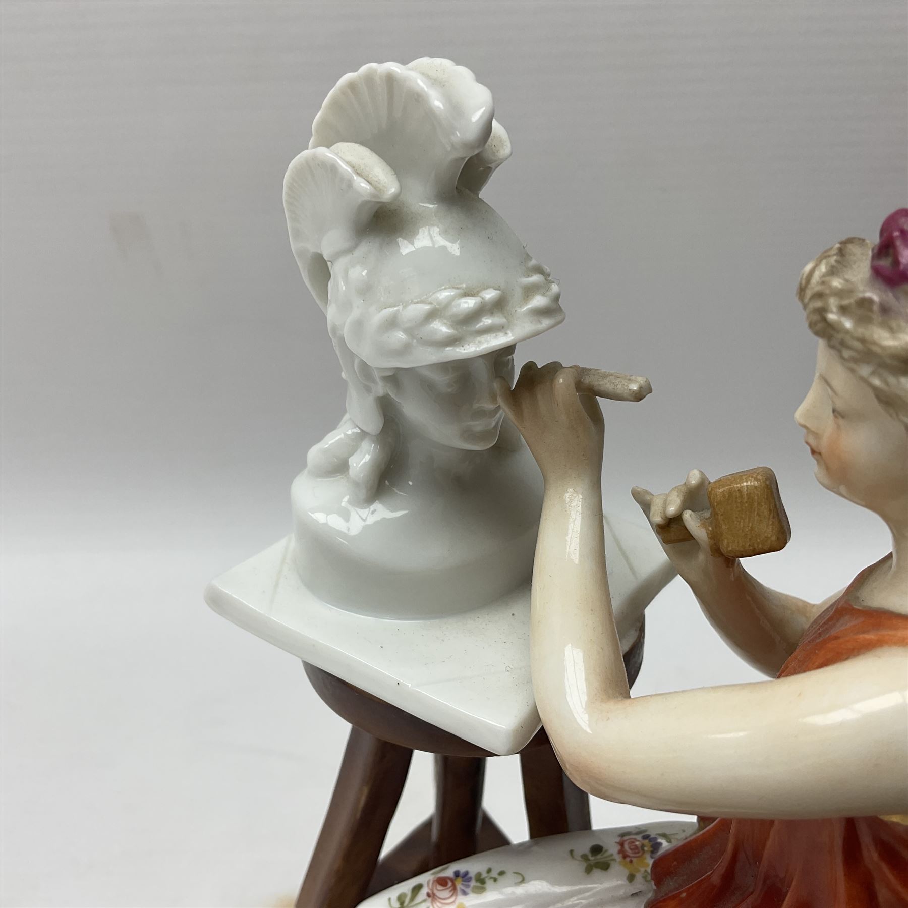 Pair of late 19th/early 20th century Naples figures modelled engaged in the arts, the first example modelled as a female figure seated before an easel, painting a figural scene, the second modelled as a female figure seated before a bust with scultping tools in hand, each upon an oval base with naturalistic painted ground, each with blue crowned N mark beneath, each approximately H16cm, including base L15xm
