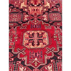 Persian Hamadan indigo and crimson ground rug, the field filled with three shaped medallions, overall geometric design, decorated with sandikli and hac motifs, geometric main border with repeating hooked motifs, within guard stripes decorated with small flower heads, outer crenelated fence band 