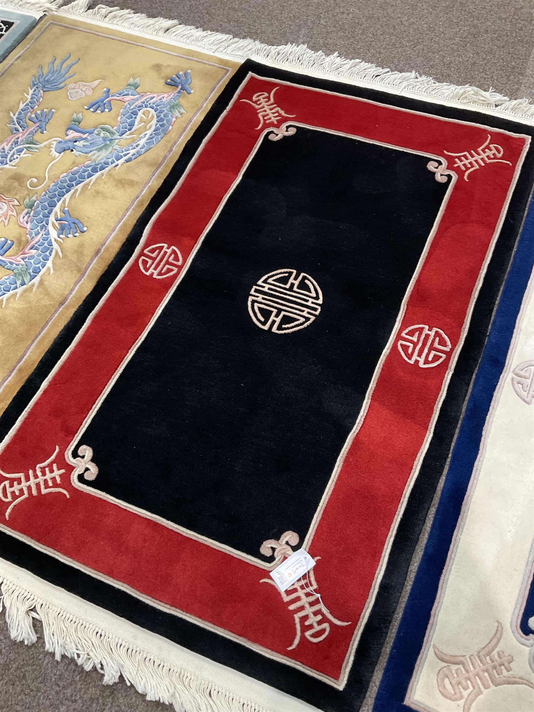 Collection of four Chinese washed woollen rugs - blue ground (153cm x 92cm); red and black ground (156cm x 94cm); light blue ground (138cm x 70cm); gold ground (153cm x 77cm)