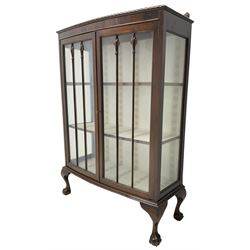 Early 20th century figured walnut bow-front display cabinet, enclosed by two glazed doors, on ball and claw cabriole feet