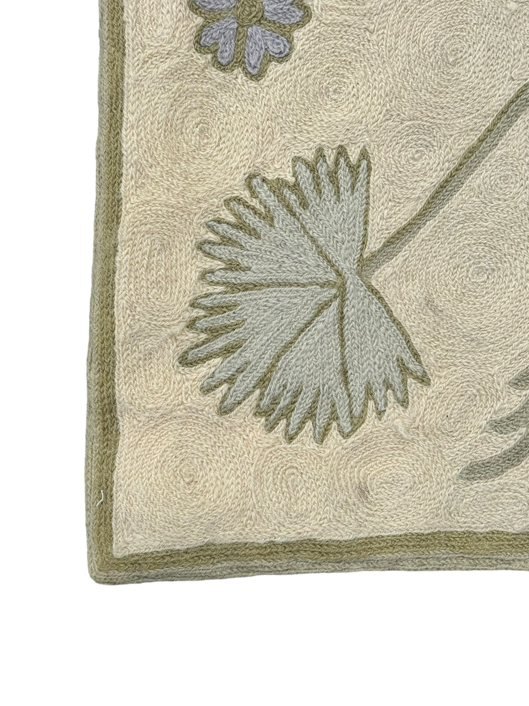 Kashmiri hand-stitched wool chain runner, featuring a cream ground decorated with meandering vines and an array of pastel flowers, enclosed by a plain light green border