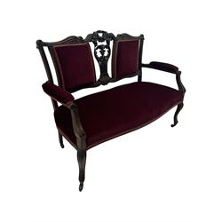 Late Victorian dark oak framed sofa, the backrests, seat and padded arms upholstered in deep red fabric, carved crest rail with scroll and foliate motifs supported by carved uprights, on cabriole supports with leaf carvings terminating in castors