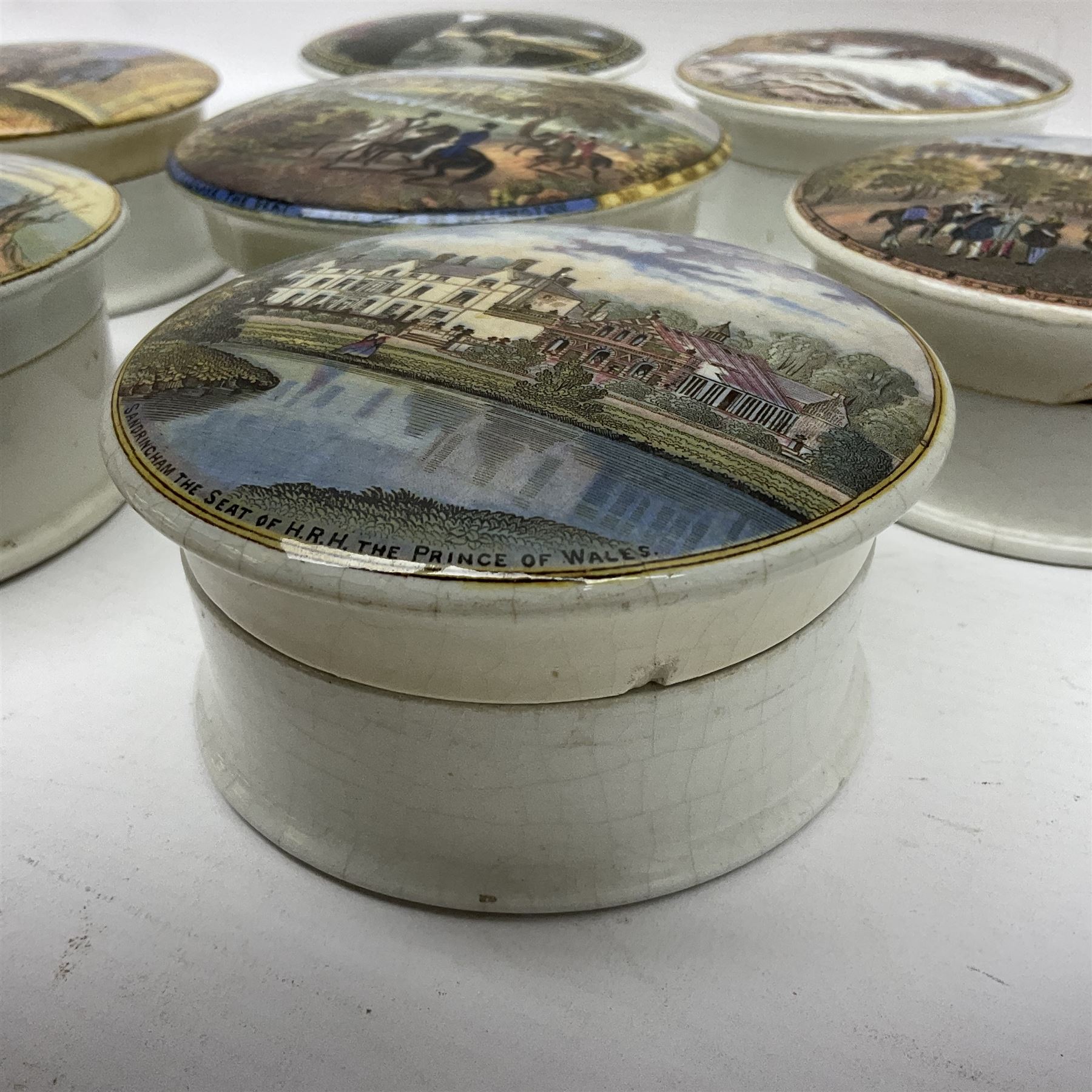 Seven 19th century Prattware pot lids with associated bases, including 'The Snow Drift', 'Strathfieldsaye The Seat of the Duke of Wellington', 'The Late Prince Consort', 'French Street Scene', Lend a Bite', 'Dr Johnson' and 'Sandringham the Seat of HRH The Prince of Wales', largest D12cm (7)