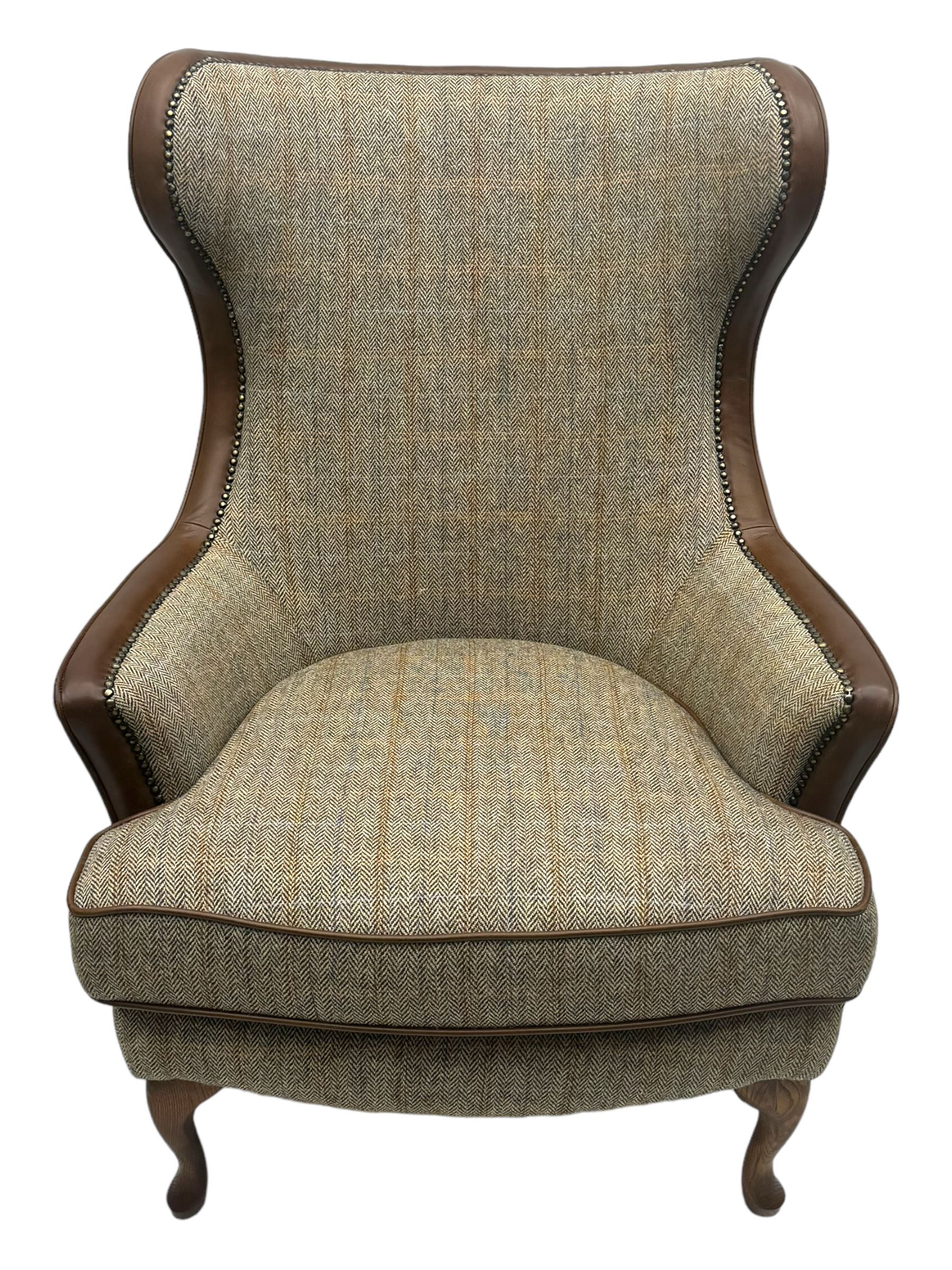 Wood Bros - contemporary wingback armchair, high back with curved wings upholstered in herringbone patterned fabric, accented with leather trim and brass nailhead studs, resting on cabriole front feet 