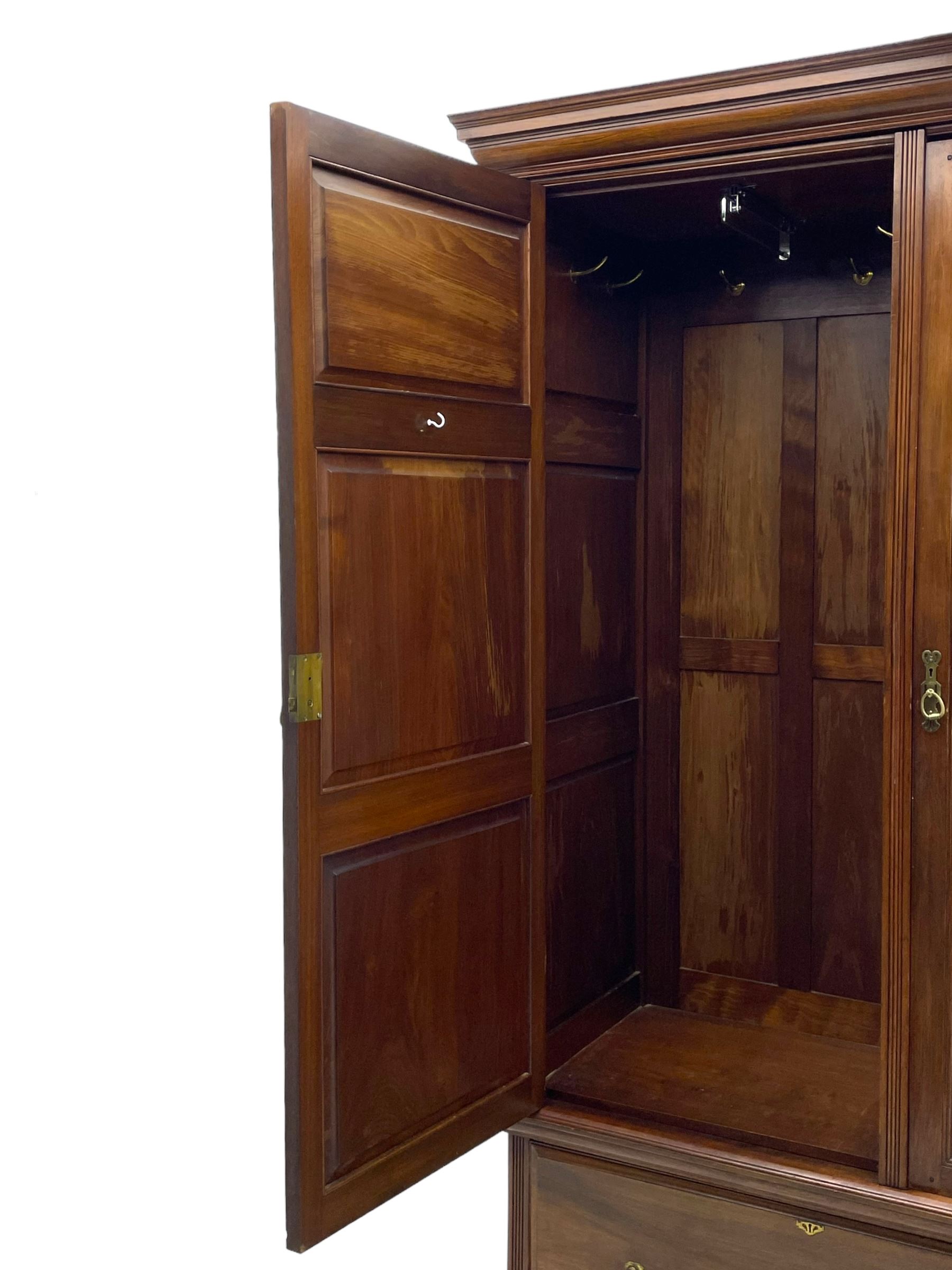 Late Victorian walnut triple wardrobe, projecting moulded cornice over central bevelled mirror door and flanking panelled doors, the top panels carved with fluted fans and stylised leaf motifs, the interior fitted with three linen slides, two drawers and hanging space, two long drawers to base, reed moulded uprights and vertical fluted horizontal rails 