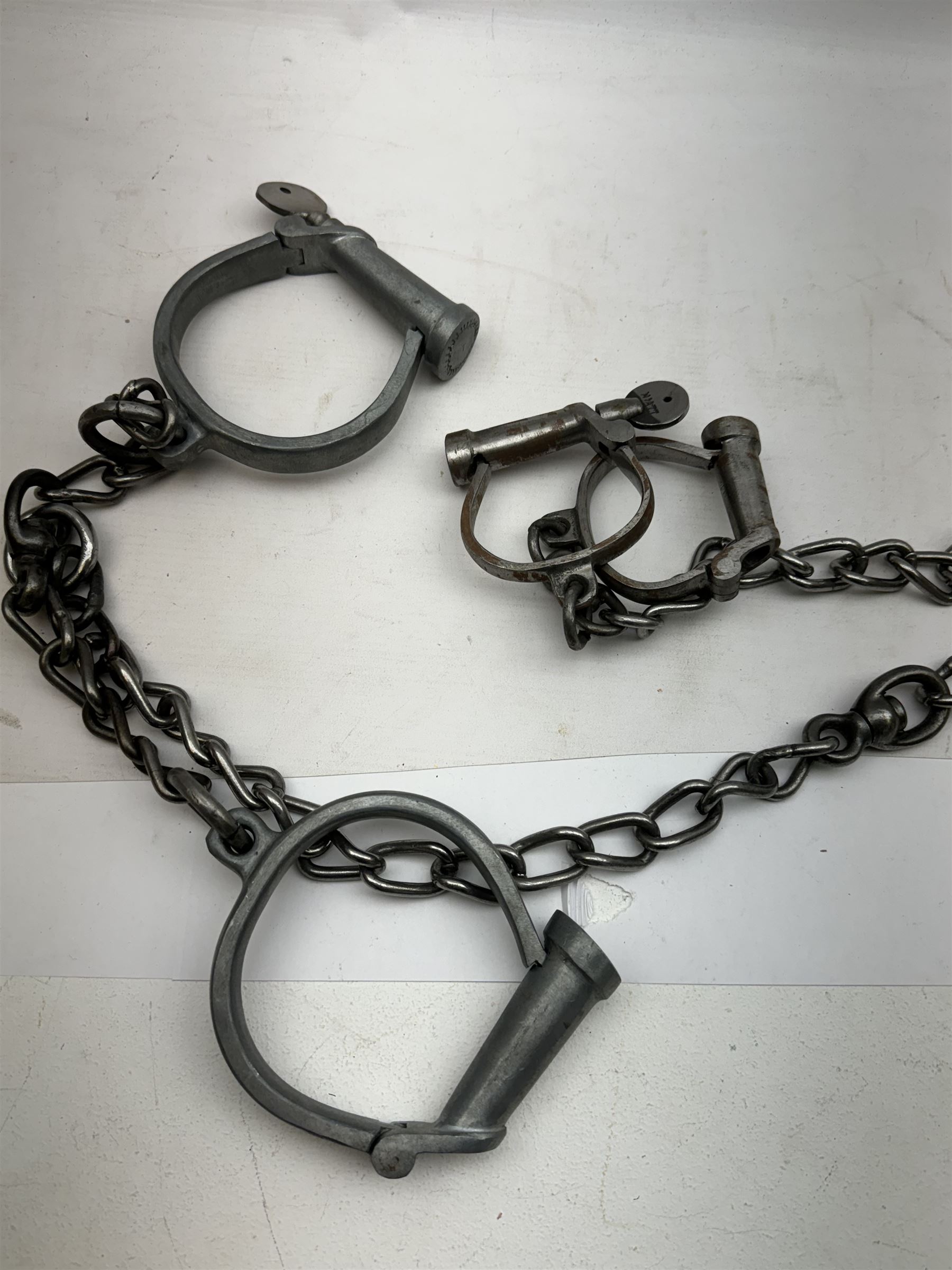 Hiatt handcuff and leg chains, together with leather collar with brass cow bells and similar items 