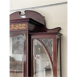 Art Nouveau period inlaid mahogany display cabinet, raised shaped and moulded pediment over projecting moulded cornices, the upper frieze inlaid with trailing branches and tulips, single astragal and bevel glazed door enclosed velvet lined interior fitted with shelves, flanked by curved glass panes decorated with pierced metal foliate spandrels, lower flanking shelves with mirror backs enclosed within shaped and pierced rails inlaid with flower heads, on tapering octagonal supports terminating to compressed pad feet, the lock stamped 'Salmon Bros, London' 