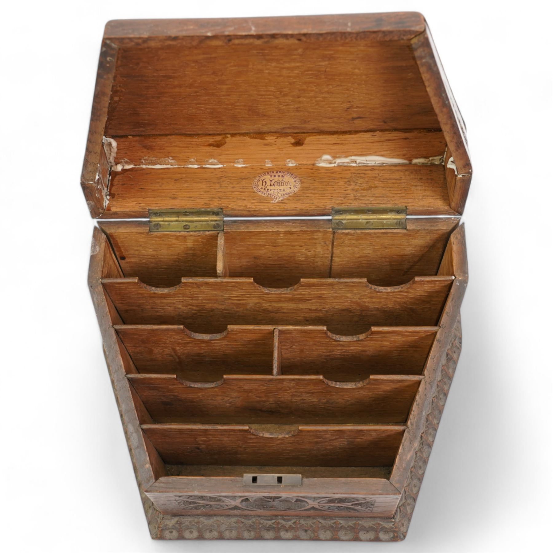 Late Victorian oak stationery box carved with Gothic and foliate panels, hinged sloping lid and divided interior with the trade label of H Ladd, 34 Trinity St. Cambridge, Stationer & Die Sinker W26cm