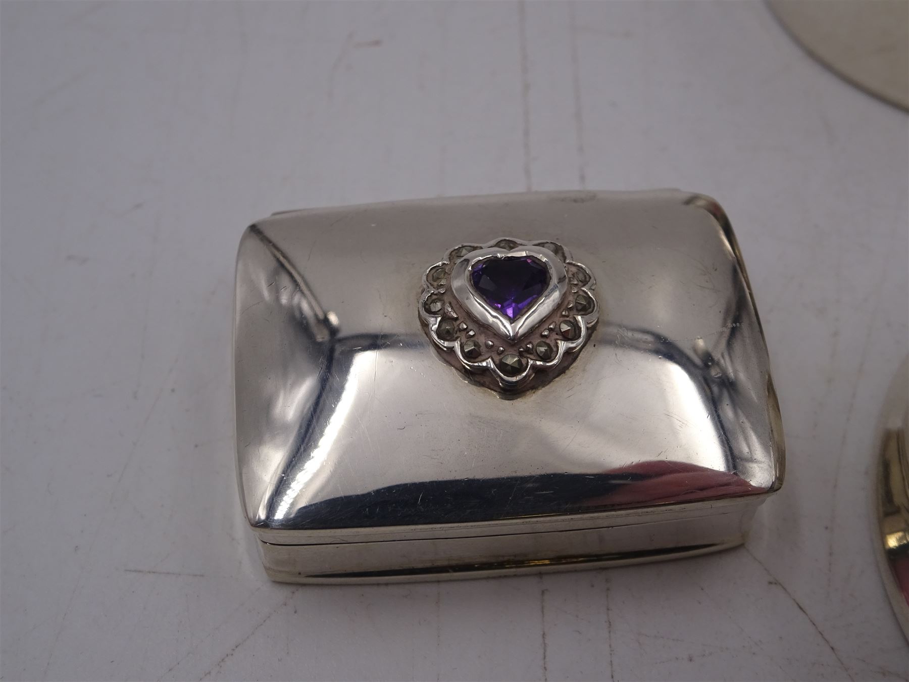 Four silver boxes, comprising oval example embossed with horse and rider, a rectangular example set with heart shaped amethyst, an oval example with set with carved abalone shell portrait, and a circular example set with Victorian penny, all hallmarked 