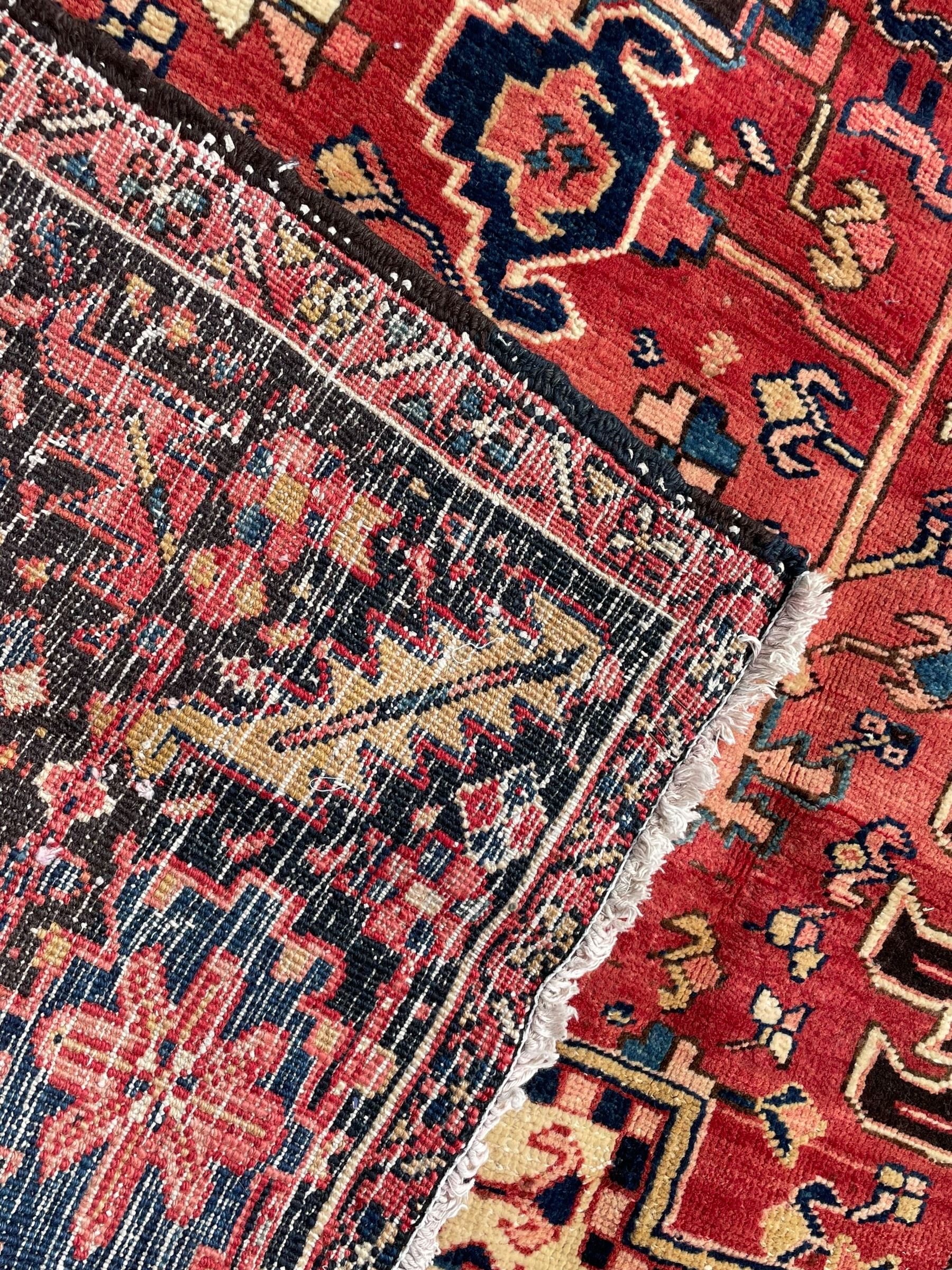 Persian Heriz red ground carpet, large central eight point medallion with projecting palmettes surrounded by small geometric motifs, decorated profusely with hooks, rosettes and animals, the busy border decorated with stylised foliate motifs within guard stripes 