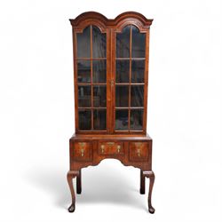 George II design walnut cabinet on stand, double arched top with applied mouldings over two astragal glazed doors, three internal shelves, the stand with moulded rectangular top fitted with three short drawers over shaped apron, on cabriole front supports 