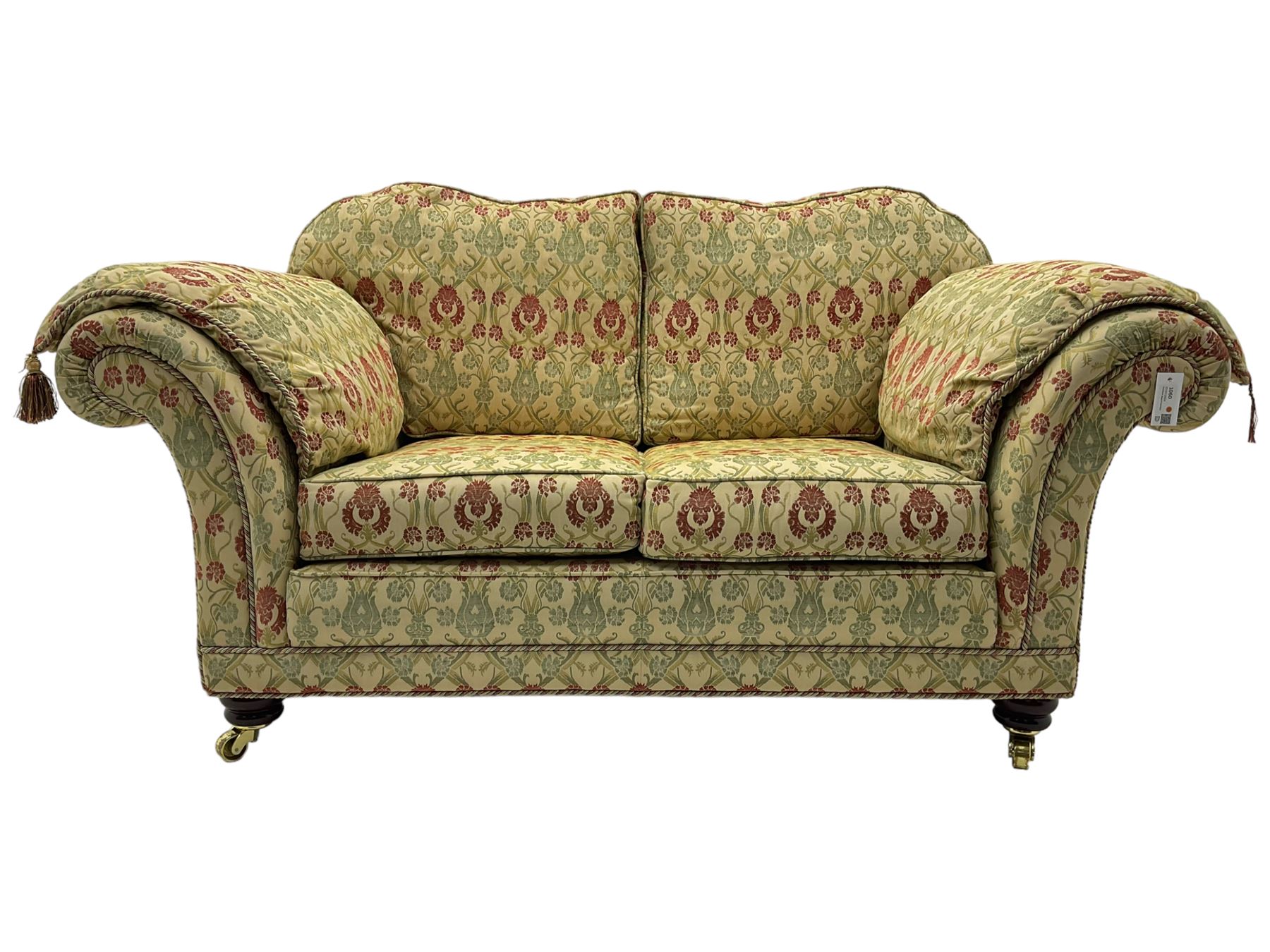 Traditional design two seat sofa, high back with scrolled arms, upholstered in beige fabric with red and green damask motifs, on castor supports (L178cm, D100cm, H89cm); matching armchair (L109cm, D89cm, H89cm)