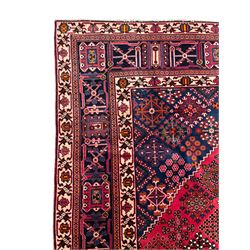 Persian Joshaghan red ground rug, the medallion, field and spandrels decorated with Pitrak and tree of life motifs, the border with repeating design decorated with stylised plant motifs, within guard stripes